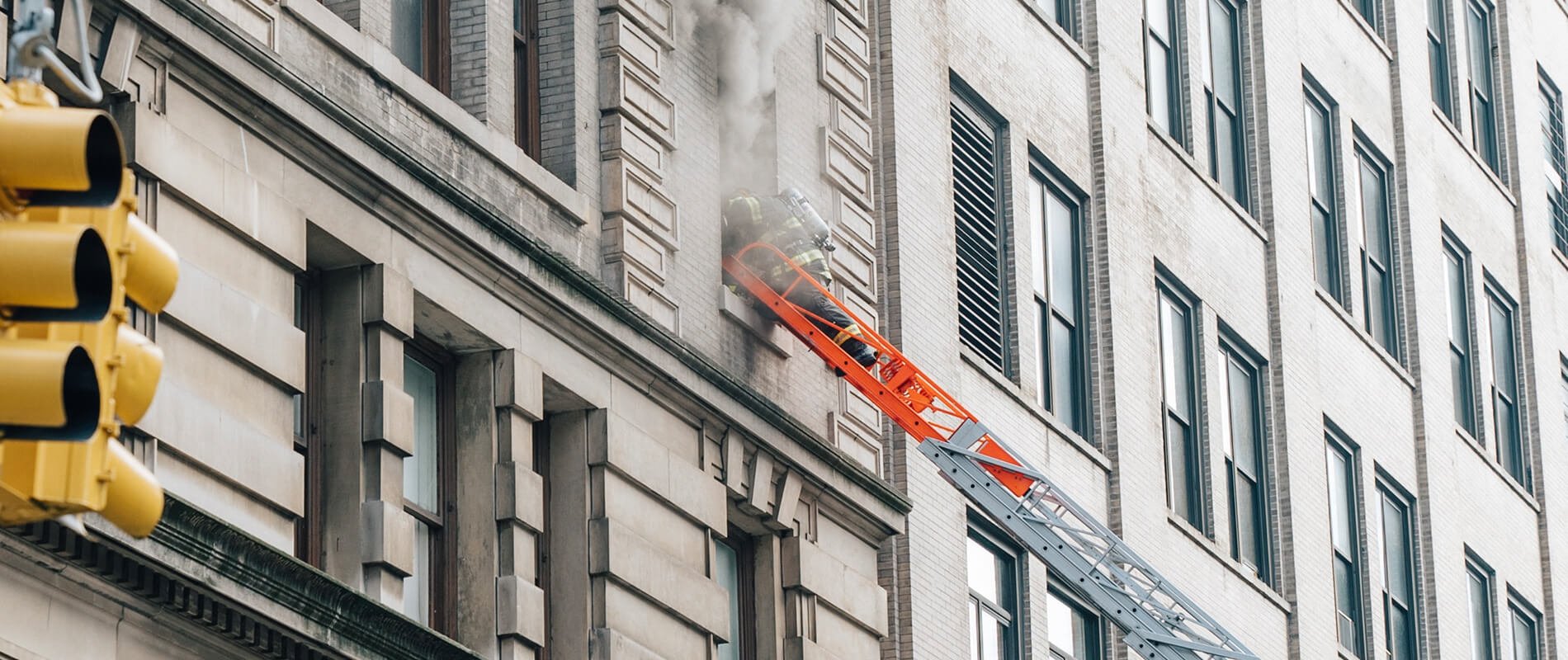 firefighter on ladder on building - self closing door hinge fire security systems installation nh